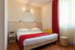 Simon Hotel في بوميتسيا: غرفة فندق عليها سرير وعليها حقيبة صفراء