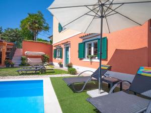 a patio with chairs and an umbrella next to a pool at Apartment Sandra by Interhome in Matulji