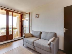 a living room with a couch and a large window at Apartment Trinquart-1 by Interhome in Seignosse