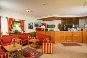 a living room with red couches and a kitchen at Hotel & Gasthof Kröll in Niedernsill