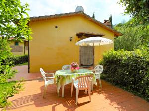 a table and chairs on a patio with a yellow house at Holiday Home Il Masso-1 by Interhome in La Collina