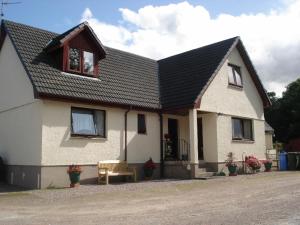 una casa blanca con techo negro en Thistle Cottage, en Fort William