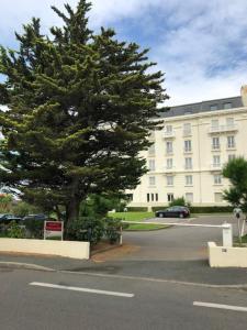 uma grande árvore num parque de estacionamento ao lado de um edifício em Studio 3* Vue Mer Parking Régina et Golf em Biarritz