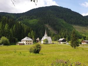 een groen veld met een kerk en een berg bij Mountain apartment Innerkrems in Innerkrems