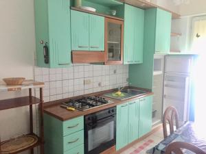 a kitchen with green cabinets and a stove top oven at Residence Regni in Senigallia