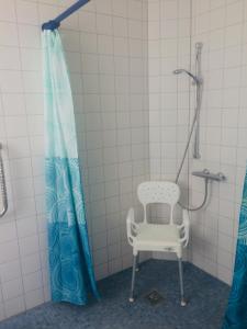 a shower with a chair and a shower curtain at Bontemps Apartment in Timmendorfer Strand