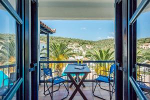 balcón con mesa, sillas y vistas en Agelos Studios, en Skopelos Town