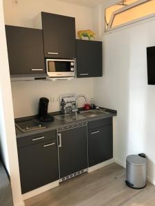 eine Küche mit schwarzen Schränken, einer Spüle und einer Mikrowelle in der Unterkunft Apartmenthaus Hamburg Eppendorfer Weg in Hamburg