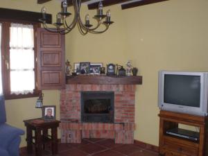 sala de estar con chimenea y TV en Posada La Pedriza, en Pontones