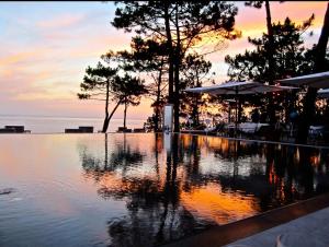 einen Pool mit Wasser und Sonnenuntergang im Hintergrund in der Unterkunft PETIT STUDIO de L'ERMITAGE in Gujan-Mestras