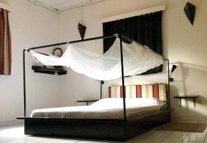 um quarto com uma cama de dossel com lençóis brancos em Auberge Djamilla em Bamako