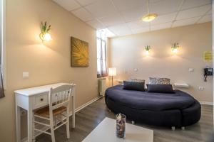 a room with two beds and a table and a desk at Hôtel des Moulins in Allauch