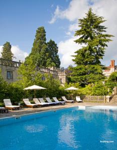 a swimming pool with lounge chairs and umbrellas at Rhinefield House Hotel in Brockenhurst