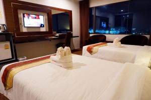 a hotel room with two beds and a television at Siam Oriental Hotel in Hat Yai