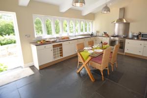 a kitchen with a table and chairs and some windows at Woodland Cottage in South Molton