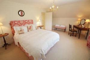 a bedroom with a large white bed and a desk at Woodland Cottage in South Molton