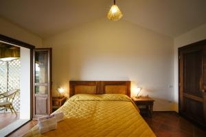 a bedroom with a bed with a yellow bedspread at Hotel Funtana Ena in Loceri