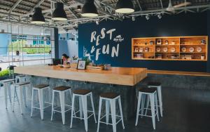 a woman sitting at a bar with stools at Blue Bed Hotel in Chanthaburi