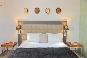 a bedroom with a bed with two tables and two clocks on the wall at Hôtel La Villa Cap d’Antibes in Juan-les-Pins
