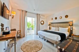 a hotel room with a bed and a desk and a window at Hôtel La Villa Cap d’Antibes in Juan-les-Pins +37 photos