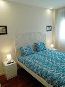 1 dormitorio con 1 cama con edredón azul y 2 lámparas en Coqueto apartamento Las Margas Golf, en Sabiñánigo