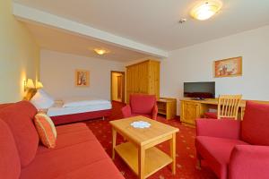 een woonkamer met een bank, een bed en een tafel bij Hotel & Gasthof Kröll in Niedernsill