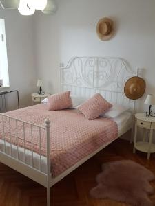 a bedroom with a white bed with pink sheets and pillows at Apartmani Antunović Podgora in Podgora