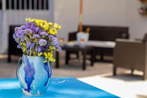 un jarrón lleno de flores moradas y amarillas en una mesa en La Locanda degli Agrumi en Trapani