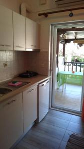 a kitchen with white cabinets and a sliding glass door at Haus Maria in Nea Potidaea