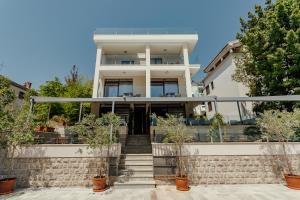 a large white house with stairs and trees at Apartments Joy in Herceg-Novi