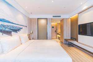 a bedroom with a large bed and a flat screen tv at Atour Hotel (Hangzhou West Lake Cultural Square) in Hangzhou