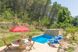 a pool with a table and chairs and an umbrella at Can Capet in Andratx