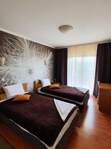 two beds in a hotel room with a mural on the wall at Kompleks Fontana in Vladičin Han