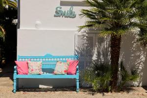 a blue bench with pink pillows next to a palm tree at Hôtel La Villa Cap d’Antibes in Juan-les-Pins