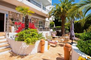 a patio with palm trees and chairs and a building at Hôtel La Villa Cap d’Antibes in Juan-les-Pins