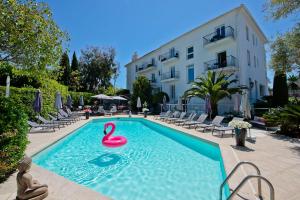 a swimming pool with a pink swan in the water at Hôtel La Villa Cap d’Antibes in Juan-les-Pins