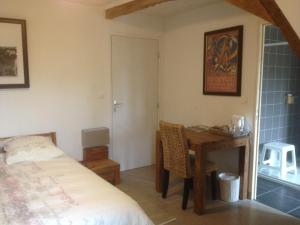 a bedroom with a bed and a desk and a table at La Grange Ô Belles in Champfrémont