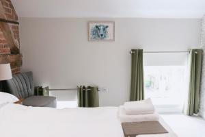 a bedroom with two beds and a chair and a window at Tuppenhurst Barn in Rugeley