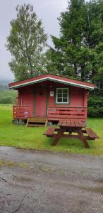 a red cabin with a picnic table in front of it at Romsdalseggen Camping in Isfjorden