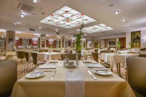 a restaurant with white tables and chairs and a skylight at Artis Centrum Hotels in Vilnius