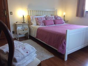 a bedroom with a bed with pink and white pillows at Apartamentos na Casa São Bernardo in Alcobaça