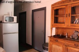 a kitchen with a refrigerator and a microwave at Hôtel le Dervois in Montier-en-Der