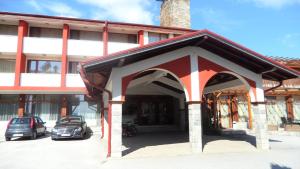 un edificio con dos coches estacionados en un estacionamiento en Paradise SPA Hotel, en Tsigov Chark