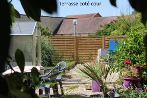a garden with a wooden fence and chairs at Hôtel le Dervois in Montier-en-Der