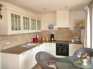 a kitchen with white cabinets and a table with chairs at Gästehaus Grothe in Zinnowitz