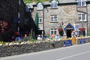 a group of people sitting outside of a stone building at Bridge House Bed & Breakfast in Boscastle