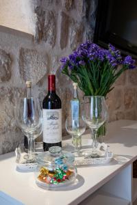 a bottle of wine and glasses on a table with flowers at Old town Marko in Dubrovnik