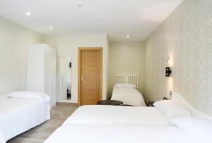 a bedroom with two white beds and a wall at Hotel Rural Oasibeth in Frómista