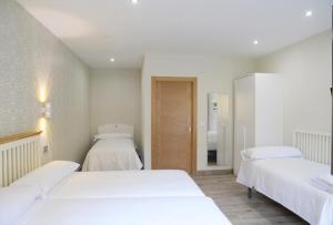 two beds in a room with white sheets at Hotel Rural Oasibeth in Frómista