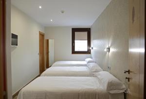 a row of four beds in a room at Hotel Rural Oasibeth in Frómista